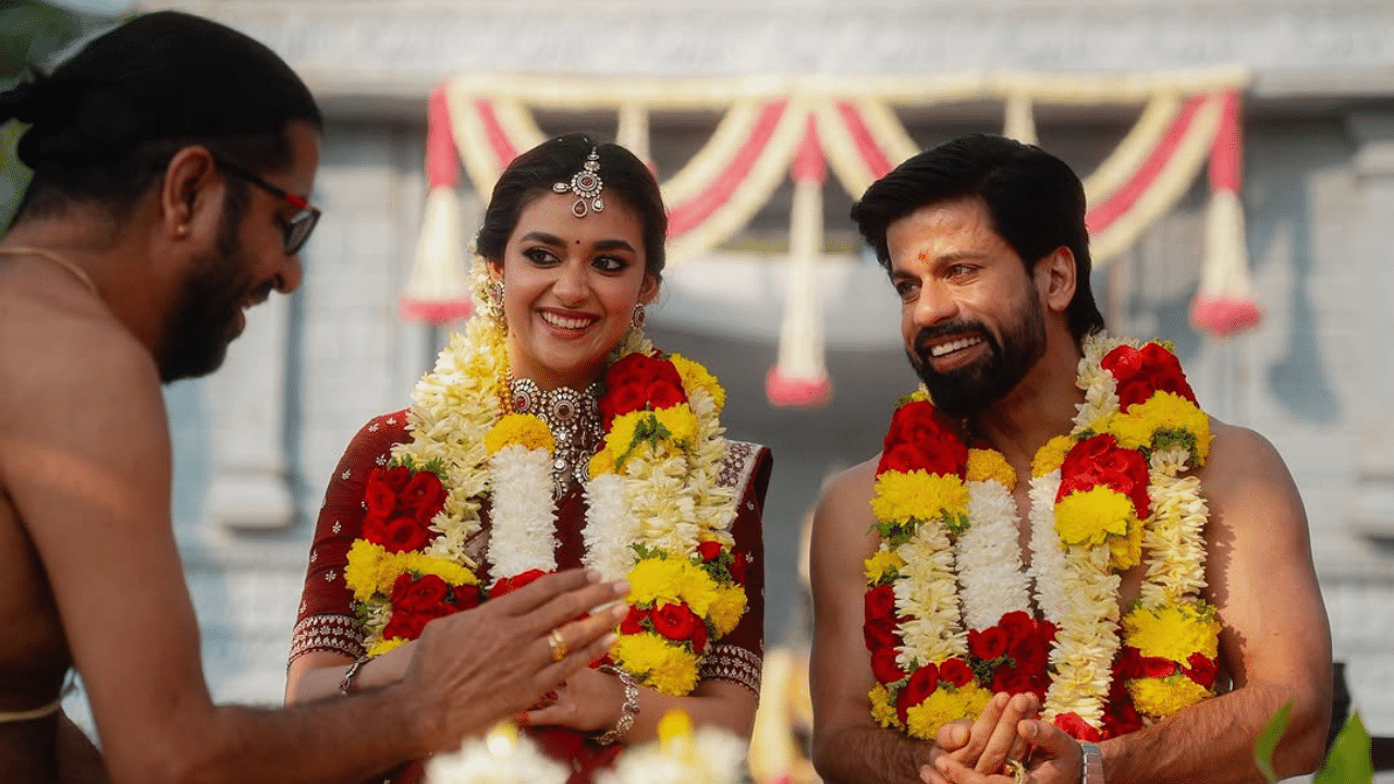 പരമ്പരാഗത രീതിയിൽ തമിഴ് സ്റ്റൈലിൽ വധുവായാണ് കീർത്തി വിവാഹത്തിന് അണിഞ്ഞൊരുങ്ങിയത്. മഞ്ഞയിൽ പച്ച ബോർഡറുള്ള പട്ടുസാരിയും, ജിമിക്കി കമ്മലും, ട്രഡീഷണൽ ടച്ചുള്ള ആഭരണങ്ങളും, നെറ്റിച്ചൂട്ടിയുമെല്ലാം ധരിച്ച് തികച്ചും ഒരു തമിഴ് ടച്ച് കീർത്തിയുടെ ലുക്കിന് ഉണ്ടായിരുന്നു. (Image Credits: Keerthy Suresh Instagram)